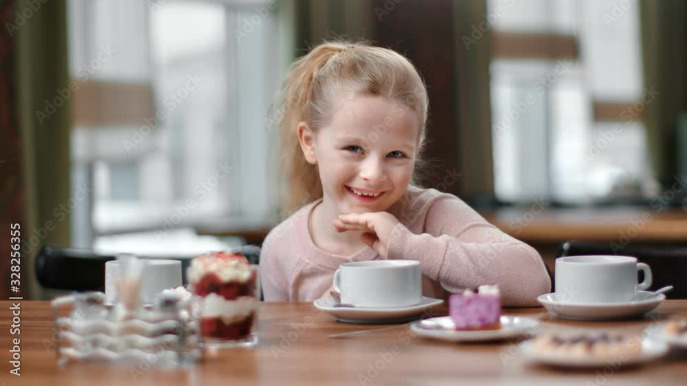 Portrait of female baby posing at cafe table with tea and delicious. Close up shot on 4k RED camera Portrait of female baby posing at cafe table with tea and delicious. Close up shot on 4k RED camera