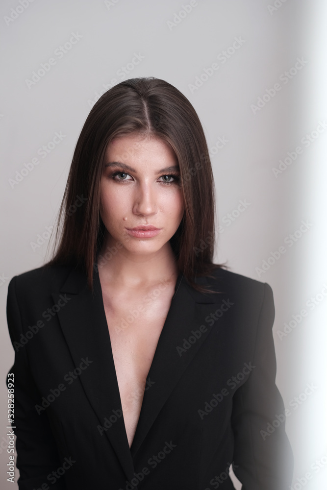 Close-up portrait of a beautiful cute girl with long hair and in a black jacket on a light background. Girl posing for the photographer in a photo studio. Close-up portrait of a beautiful cute girl with long hair and in a black jacket on a light background. Girl posing for the photographer in a photo studio.