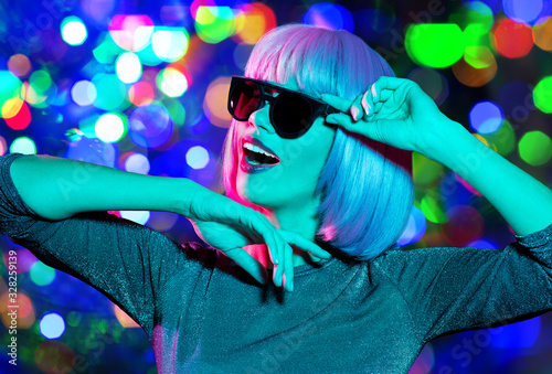 nightlife  fashion and people concept - happy young woman wearing pink wig and black sunglasses dancing over night lights background