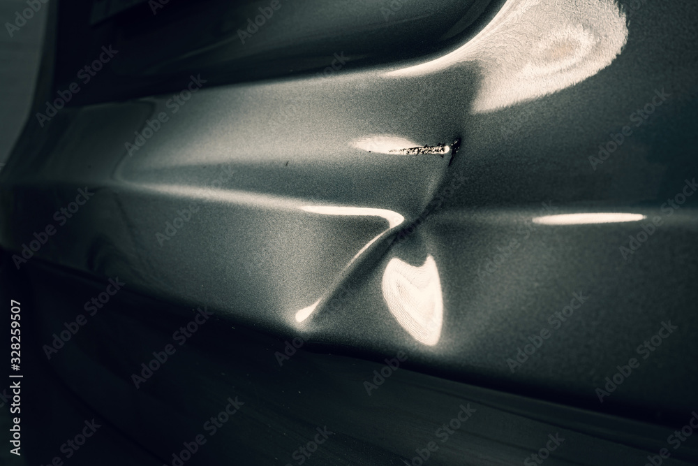A dent in the body of a silver car in exciting light. - obrazy, fototapety, plakaty 