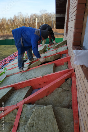Man installs a thermal insulation layer on the roof - using mineral wool panels.
