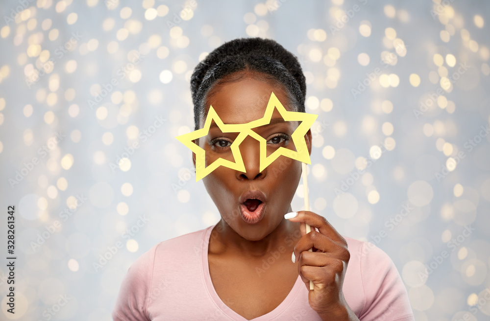 party props, photo booth and people concept - surprised african american young woman with star shaped glasses over festive lights background party props, photo booth and people concept - surprised african american young woman with star shaped glasses over festive lights background