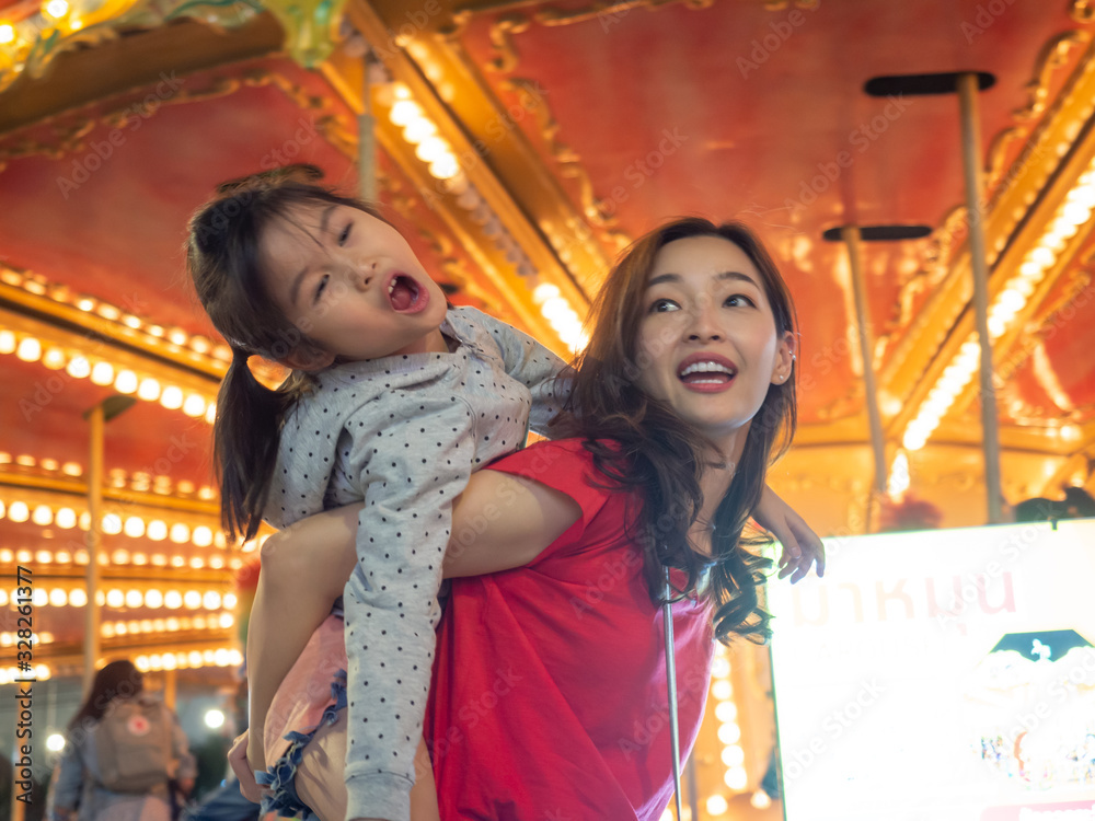 happy asia mother and daughter have fun in amusement carnival park with farris wheel and carousel background happy asia mother and daughter have fun in amusement carnival park with farris wheel and carousel background