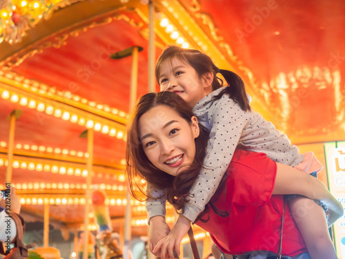 Vászonkép happy asia mother and daughter have fun in amusement carnival park with farris w