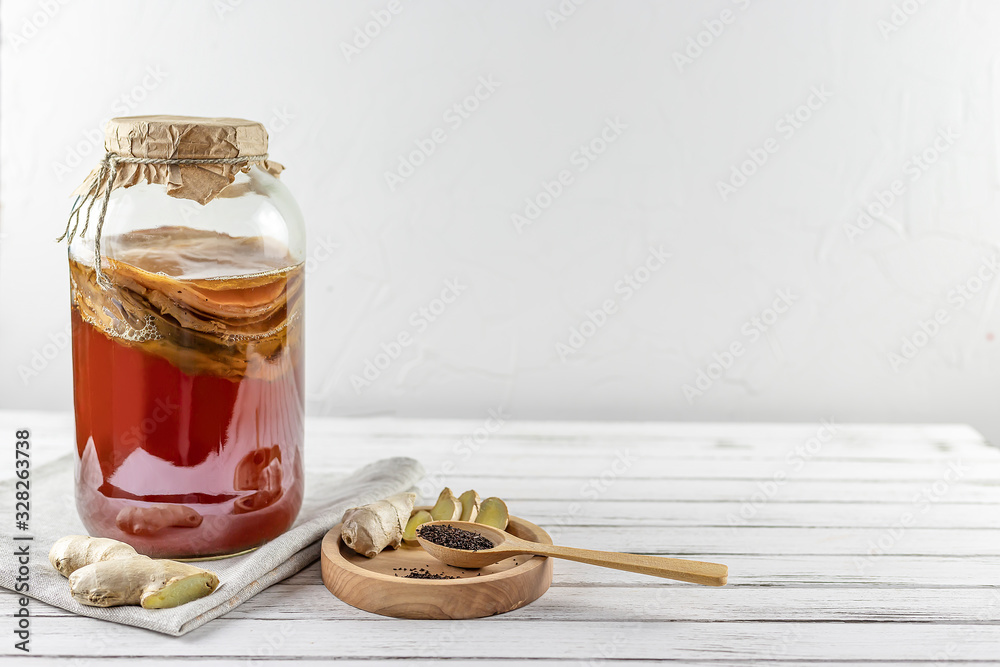 Kombucha superfood pro biotic tea fungus beverage in glass bottle and jar with ginger, tea on white background Kombucha superfood pro biotic tea fungus beverage in glass bottle and jar with ginger, tea on white background