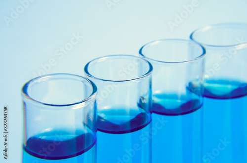 Test glass tubes with blue liquid, macro, selective focus. Laboratory test tubes. test tube with liquid sample on light blue background, closeup. Medical concept. 