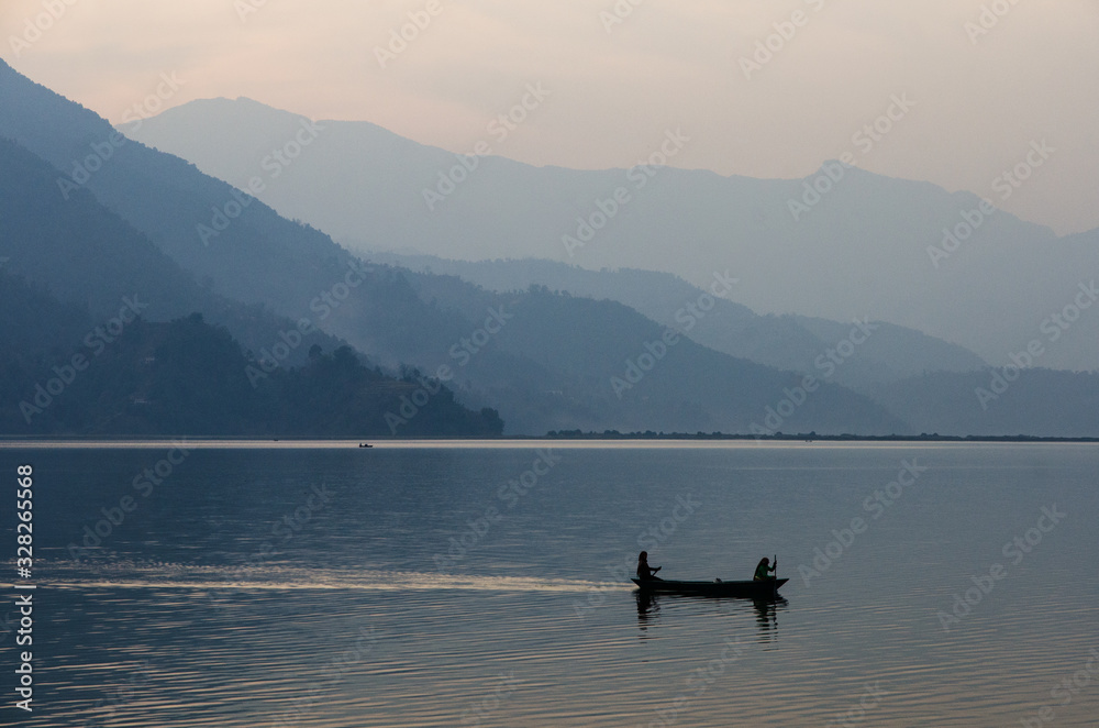 Pescadores avanzando por un lago tranquilo sobre una barca de madera Pescadores avanzando por un lago tranquilo sobre una barca de madera