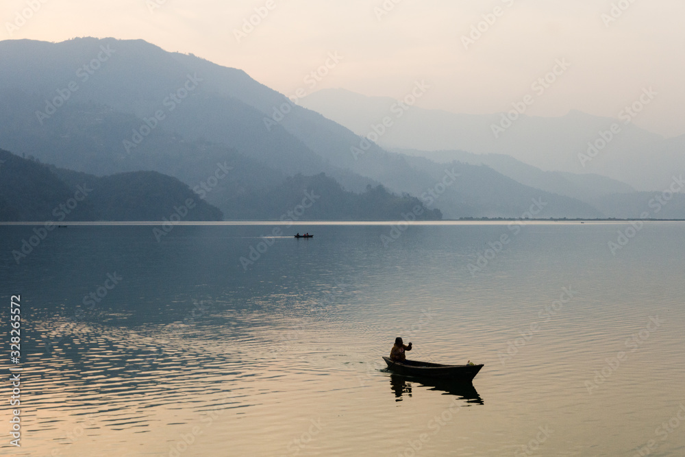 Persona solitaria remando en una barca de madera en un lago tranquilo de Nepal