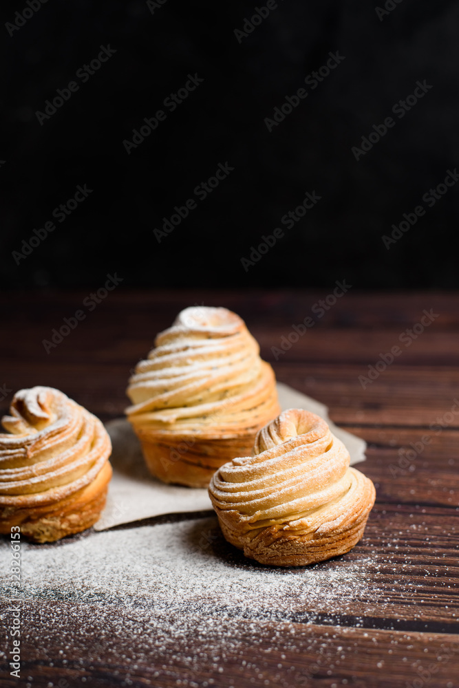 modern cruffins are made from puff croissants in the form of a muffin. on a dark background in powdered sugar. Copy space. the view from the top. close up modern cruffins are made from puff croissants in the form of a muffin. on a dark background in powdered sugar. Copy space. the view from the top. close up