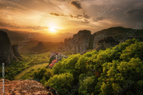 Monastery Meteora Greece. Stunning spring panoramic landscape at sunset. View at mountains and green forest against epic sky with clouds. UNESCO heritage list object. The Holly Monastery of Rousanou.
