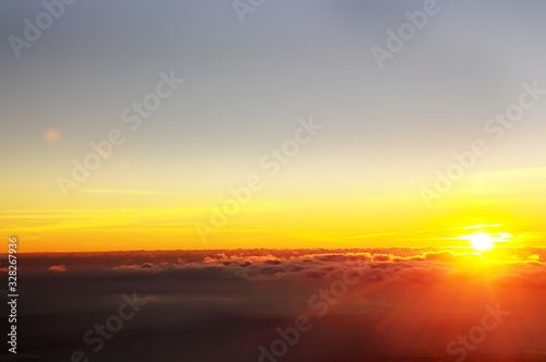 The sun rising from the clouds and fog. Top view from the mountain to a beautiful foggy distance. © Ann Stryzhekin