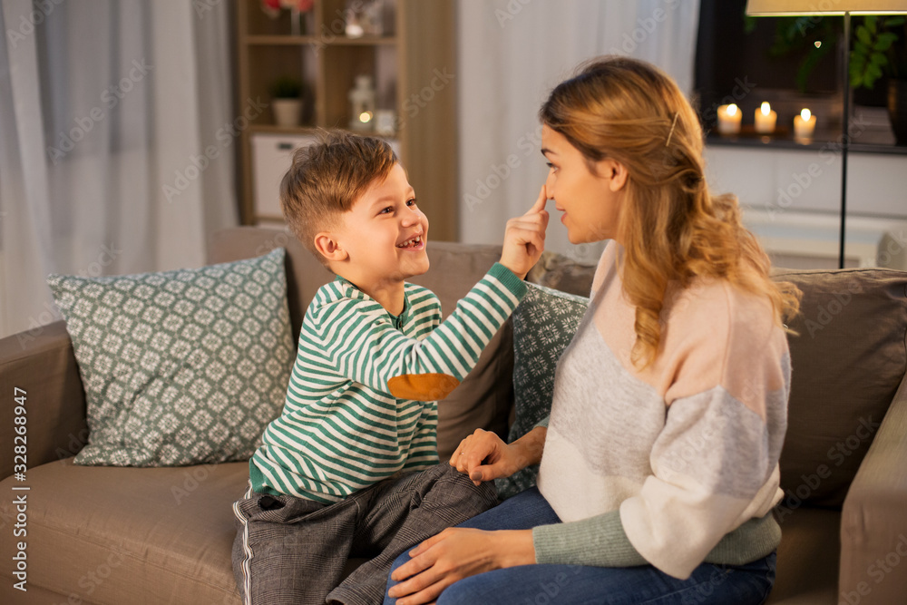 family, love and people concept - happy smiling mother touching her little son's nose at home in evening family, love and people concept - happy smiling mother touching her little son's nose at home in evening
