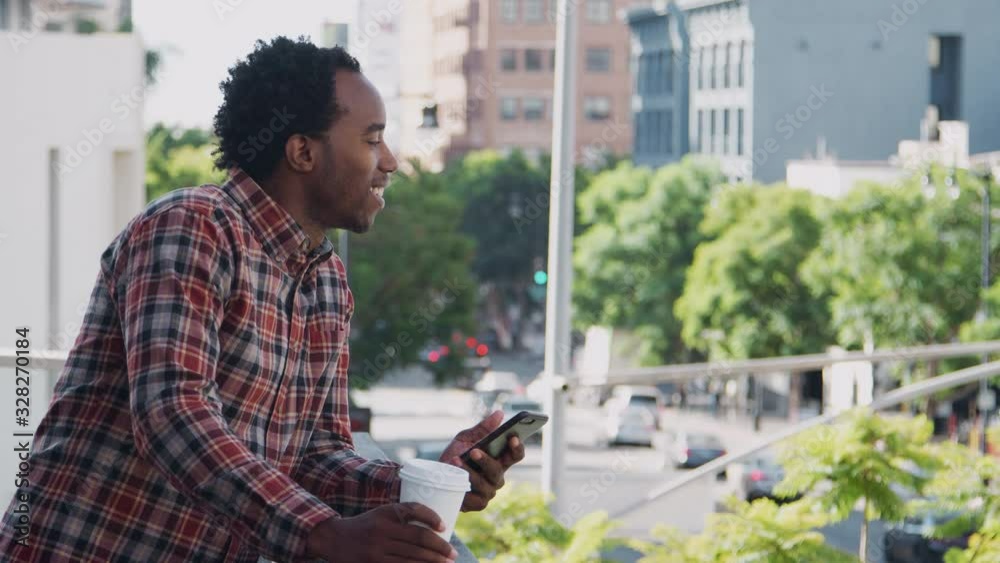 Businessman standing outside office building using mobile phone with city skyline in background - shot in slow motion Businessman standing outside office building using mobile phone with city skyline in background - shot in slow motion