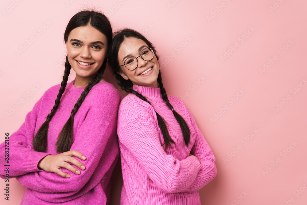 Image of two happy teenage girls in casual clothes smiling at camera Image of two happy teenage girls in casual clothes smiling at camera