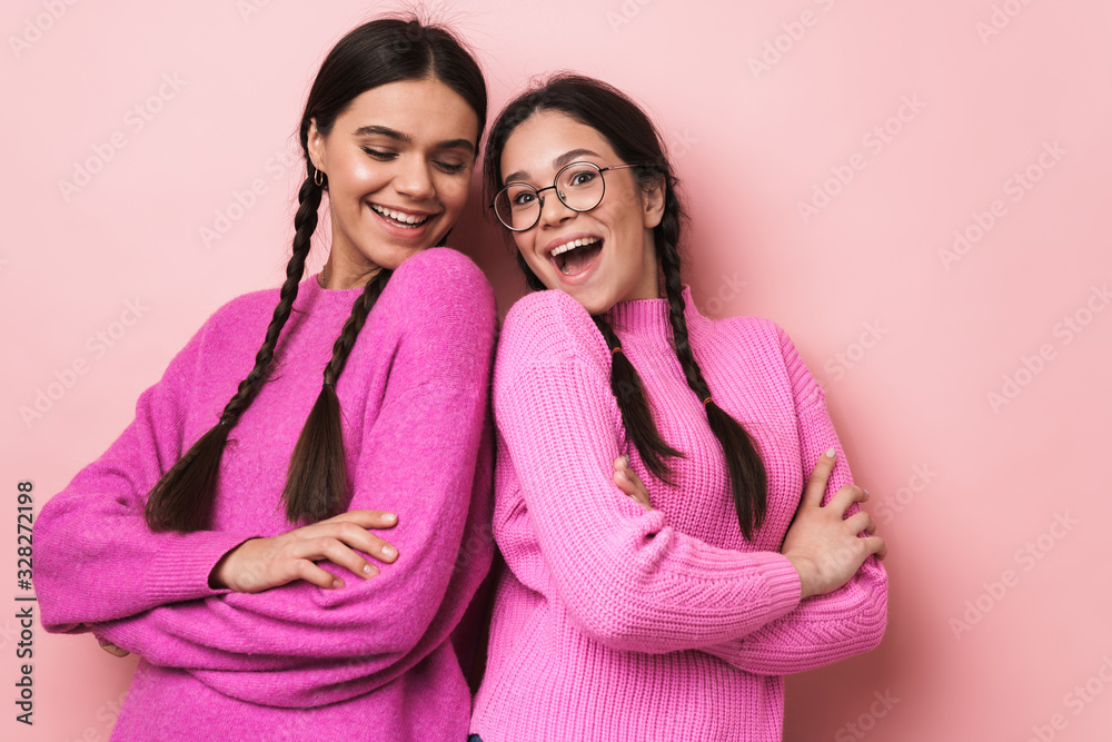 Two cheerful cute teenage girls standing back to back Two cheerful cute teenage girls standing back to back