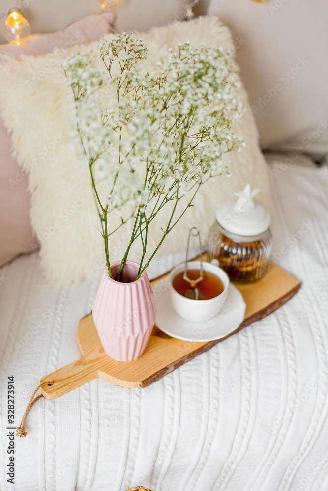 Spring home cozy interior. A bouquet of flowers in a vase, a cup of tea, decor on the sofa.