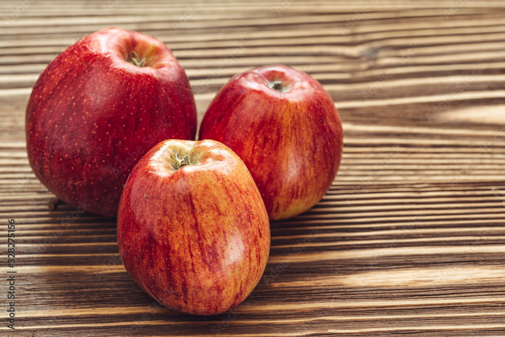 three red striped apples on wooden background. daylight three red striped apples on wooden background. daylight