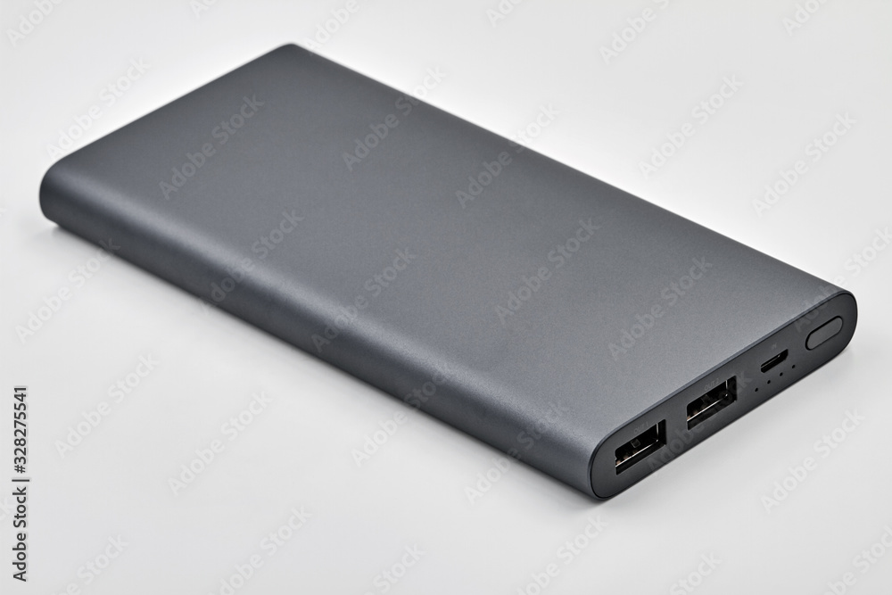External dark powerbank with two usb outputs on a white background. Powerbank for charging mobile devices. Closeup External dark powerbank with two usb outputs on a white background. Powerbank for charging mobile devices. Closeup