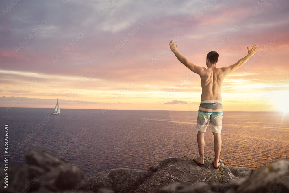 Fototapeta premium Happy man with raised arms on top of a sea cliff