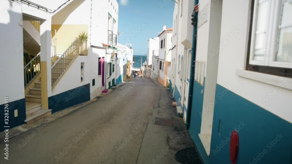 Point of view of someone walking through colourful street of a little village in Portugal.