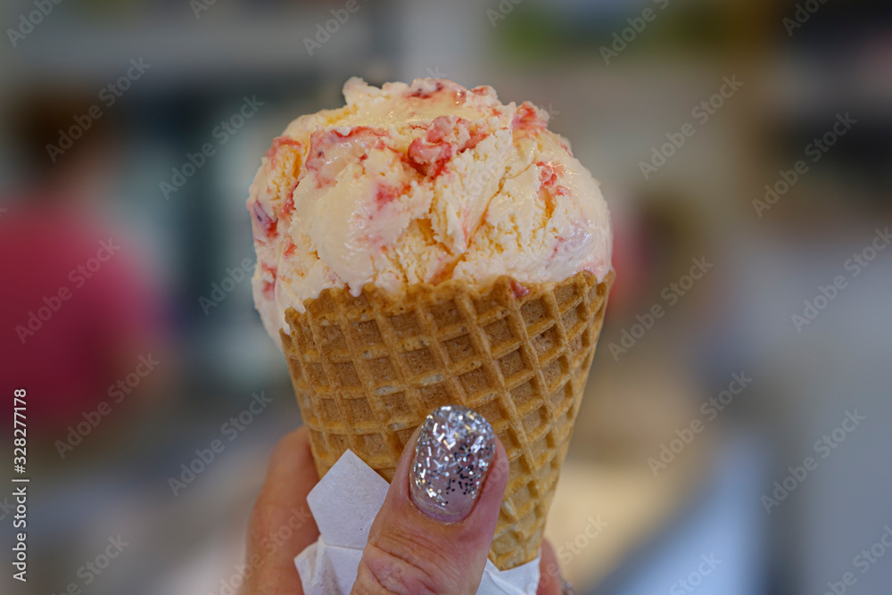 a womans hand is holding a yellow with red ice cream