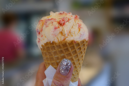 Obraz na płótnie a womans hand is holding a yellow with red ice cream w salonie