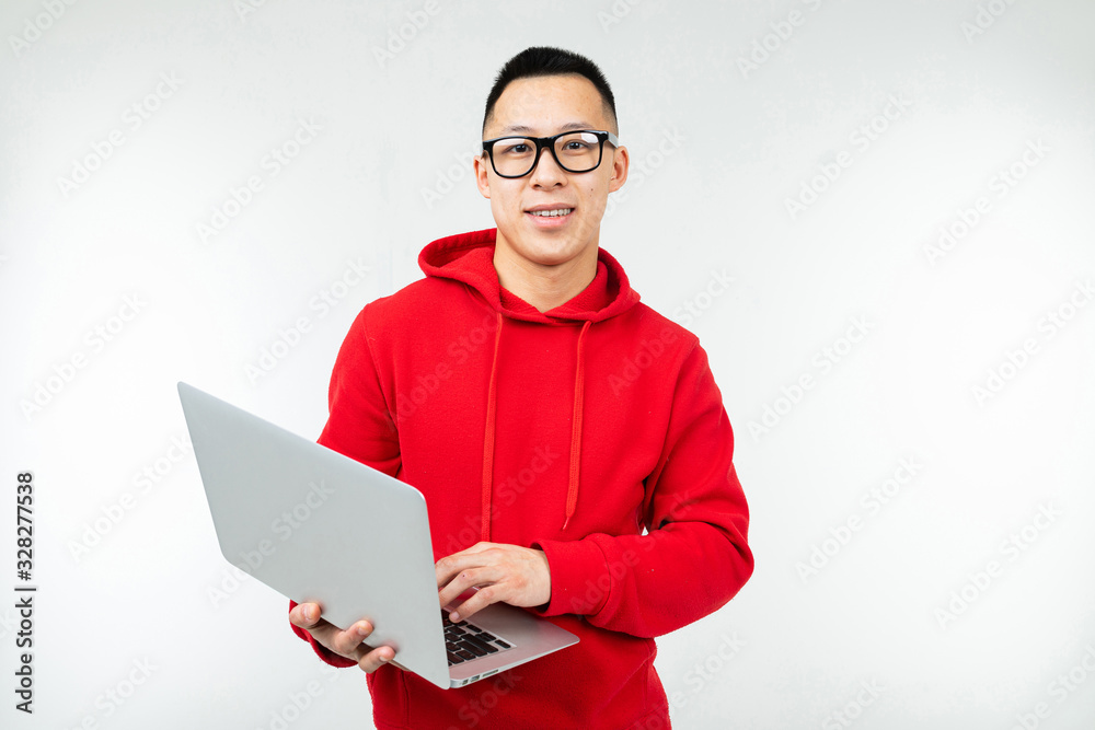 attractive brunette man in casual red hoodie with a laptop in his hands on a white studio background