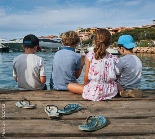 Children kids enjoying the summer with ice cream and flip-flops next to the sea on a pier