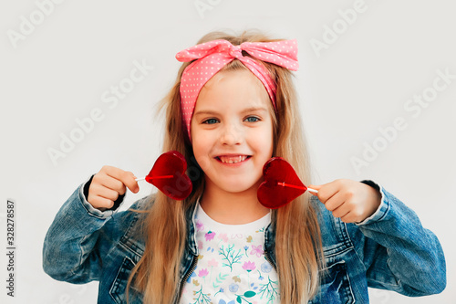 Portrait of a beautiful stylish fashionable girl in glasses, with a heart-shaped lollipop, on a white background, free time summer vacation #328278587