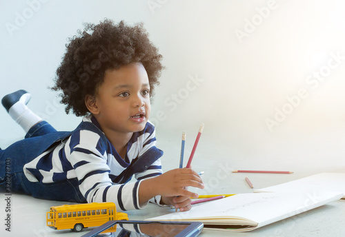 Lovely african boy happy drawing a toy in room.