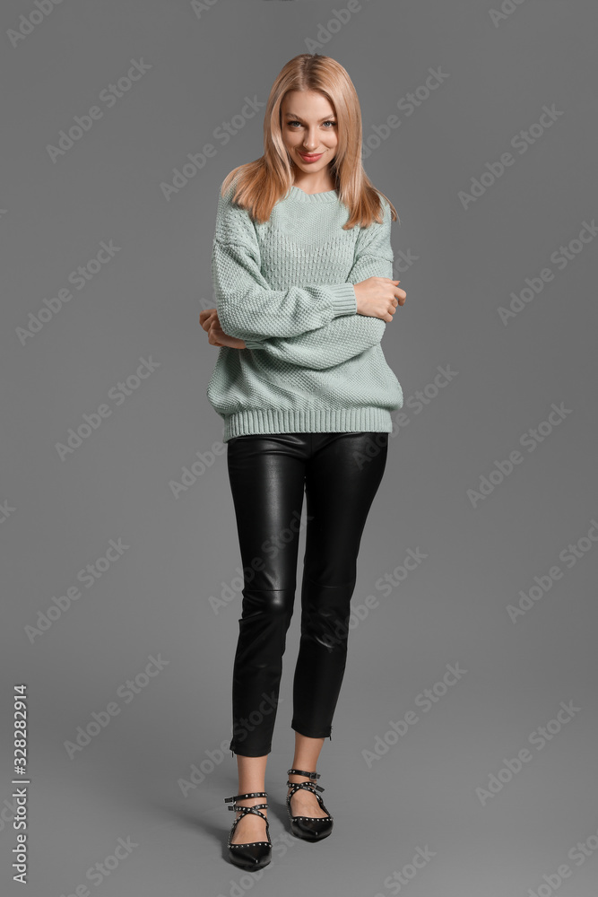 Young woman in warm sweater on grey background Young woman in warm sweater on grey background