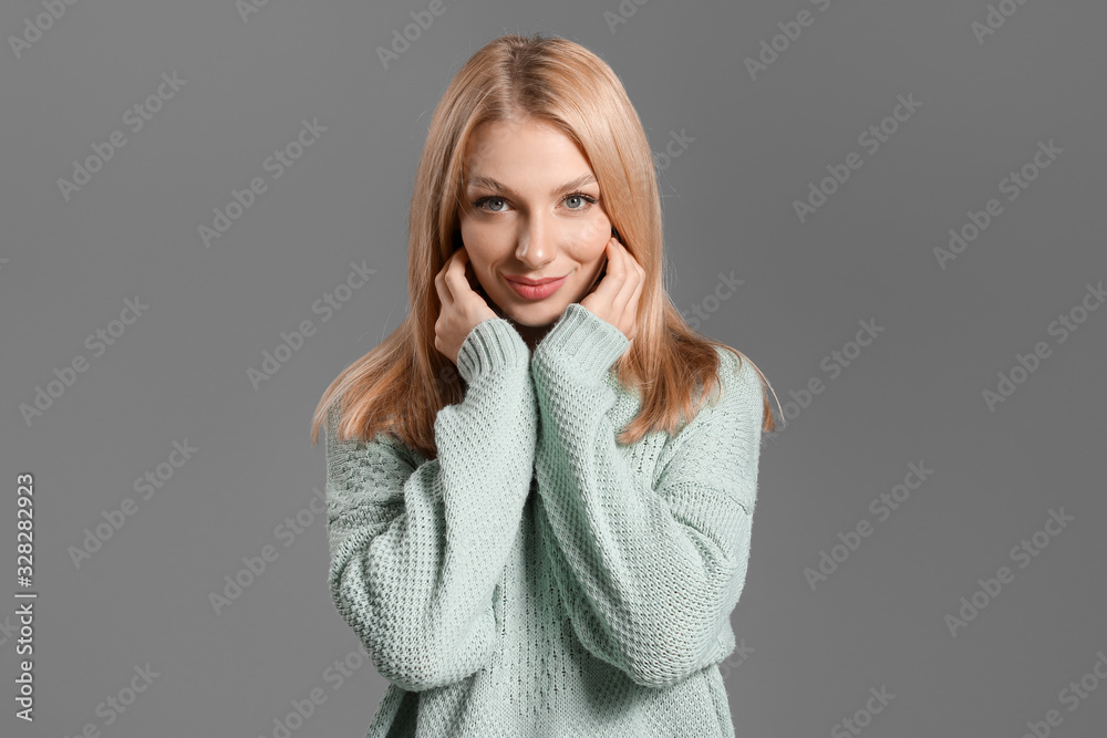 Young woman in warm sweater on grey background Young woman in warm sweater on grey background