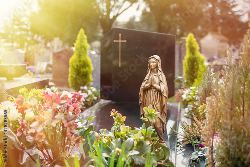 Fototapeta Virgin Mary at cemetery, graveyard background, tombstone, sunlight tone