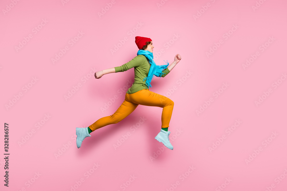 Full size profile side photo of cheerful charming girl jump up run after spring time discounts wear shoes red blue sweater pants headwear isolated over pink color background