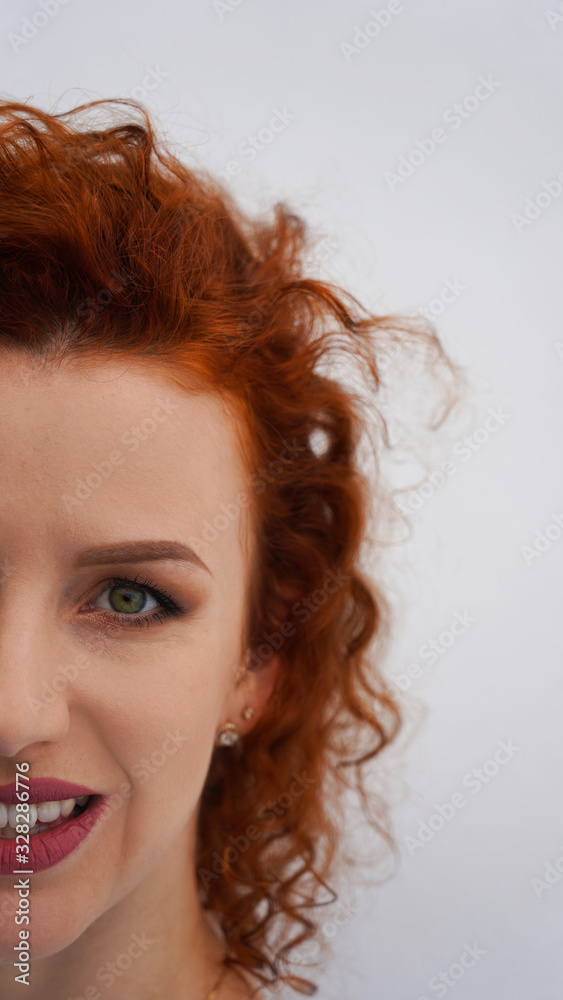 Green eyes of a beautiful red-haired curly-haired girl. long eyelashes, make up eyebrows. a look into the future. emotions, joy, laughter, fun. White background Green eyes of a beautiful red-haired curly-haired girl. long eyelashes, make up eyebrows. a look into the future. emotions, joy, laughter, fun. White background