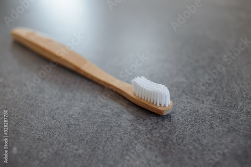 Closeup of a wooden toothbrush. Bamboo biodegradable eco toothbrush against a gray background with copy space. Plastic free concept.  Place for text