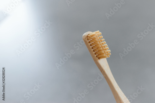 Closeup of a wooden toothbrush. Bamboo biodegradable eco toothbrush against a gray background with copy space. Plastic free concept. Place for text