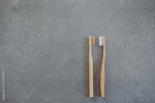 Biodegradable bamboo toothbrushes lie on a gray stone background. The concept of environmental protection, nature conservation. Zero plastic, zero waste. Ecology plastic free. Flat lay. Top view. Text