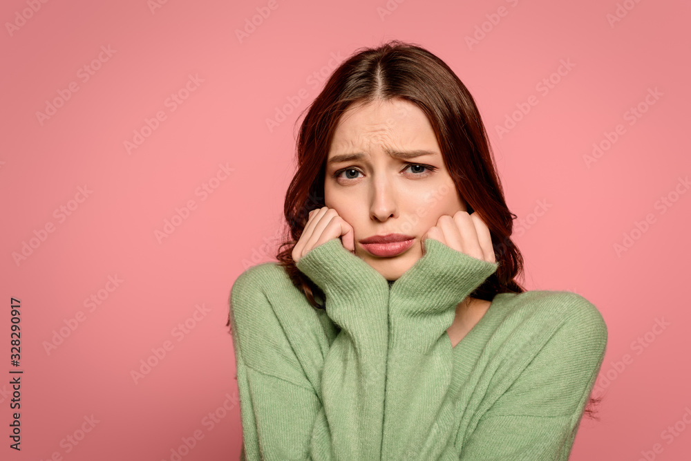 offended girl looking at camera while holding hands near face isolated on pink offended girl looking at camera while holding hands near face isolated on pink