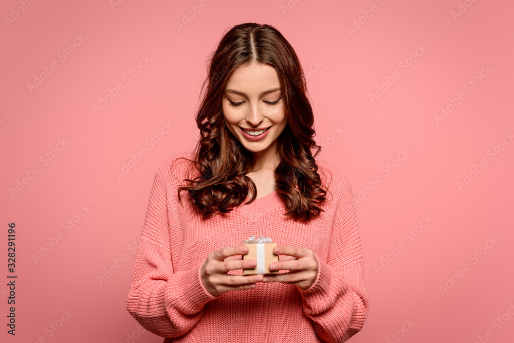 happy girl looking at small gift box isolated on pink happy girl looking at small gift box isolated on pink