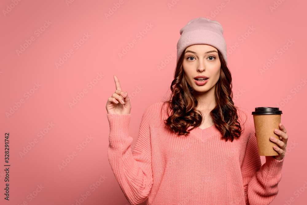 pensive girl showing idea gesture while holding coffee to go on pink background pensive girl showing idea gesture while holding coffee to go on pink background