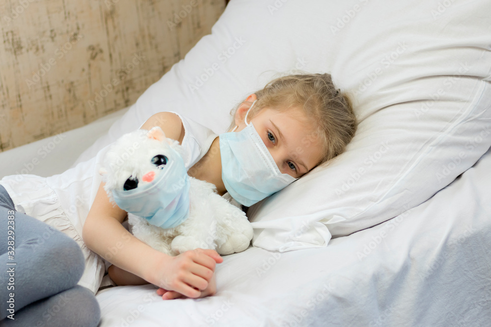 A girl with white hair in a medical mask on her face. Nearby, a soft toy on her face is also a cough mask. Close-up A girl with white hair in a medical mask on her face. Nearby, a soft toy on her face is also a cough mask. Close-up
