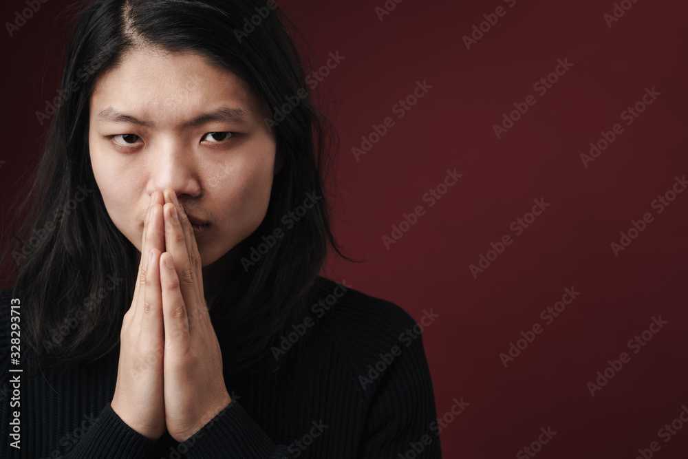 Image of focused asian man posing on camera with palms together Image of focused asian man posing on camera with palms together