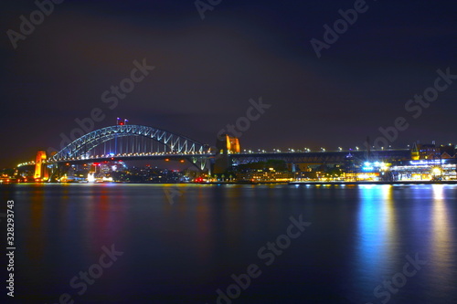Sydney Harbour Bridge illuminating the harbour and circular quay with vibrant colourful lights at midnight in NSW Australia © Elias Bitar