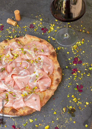 Rustic mortadella topped pizza with red wine at Italian restaurant