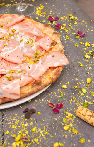 Rustic mortadella topped pizza with red wine at Italian restaurant
