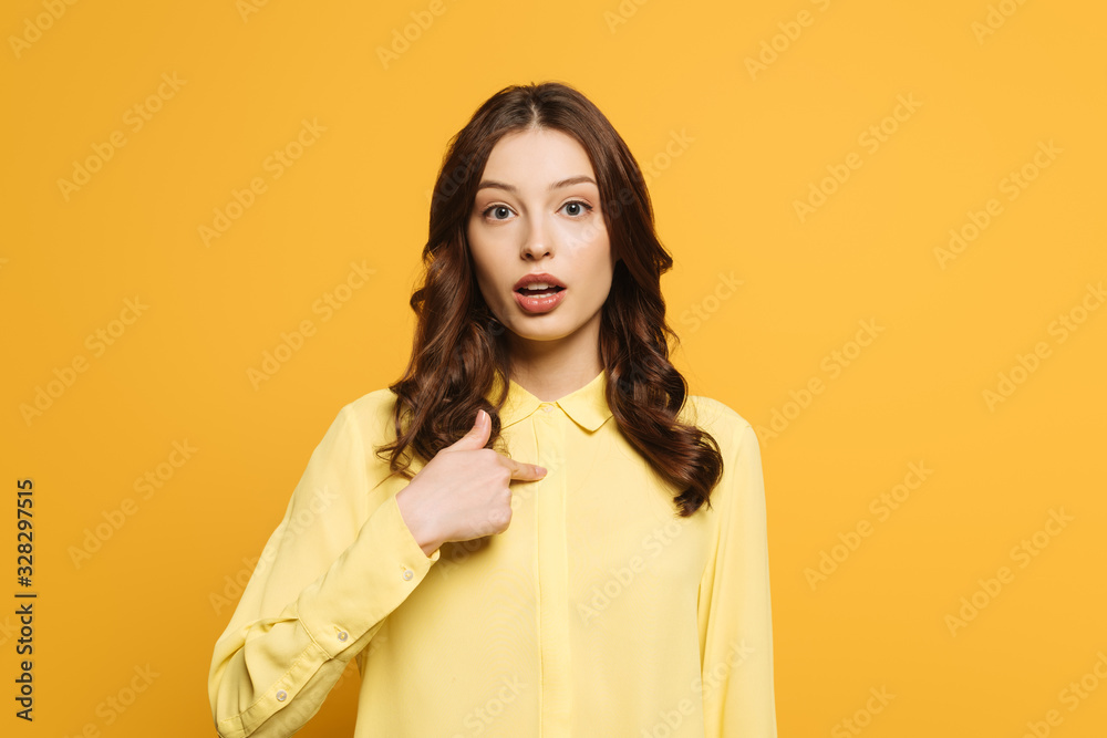 surprised girl pointing with finger at herself while looking at camera isolated on yellow surprised girl pointing with finger at herself while looking at camera isolated on yellow