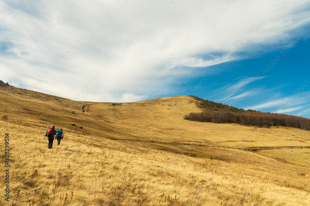 backpack hiking life style touristic landscape photography of two people back to camera walking highland Carpathian mountain environment in Ukraine