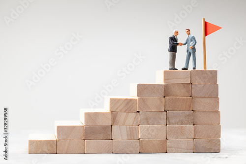 Steps up as a symbol of the path to the goal. Businessmen shake hands as a symbol of teamwork towards a common goal