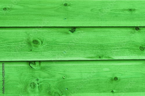 Texture of a fragment of a wooden house wall. The wall is painted green color